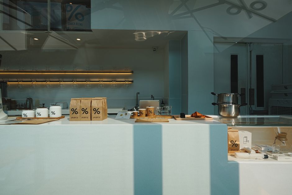 Cultura do Café — Stylish coffee shop interior showcasing retail items and brewing equipment on a minimalist counter.